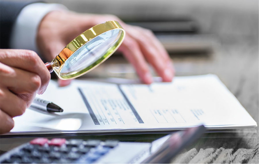 A business person uses a magnifying glass on a document