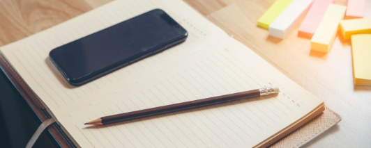 a smartphone and pencil on top of a notepad